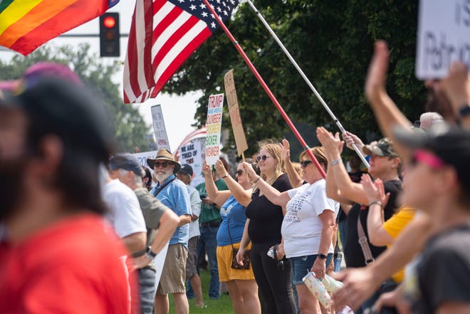 Manifestantes acenam para carros que trafegam pela East Grand Avenue durante um protesto de Fúria Contra o Regime no Capitólio Estadual de Iowa, em 2 de agosto de 2025, em Des Moines. O protesto contou com a participação de outros em todos os Estados Unidos.